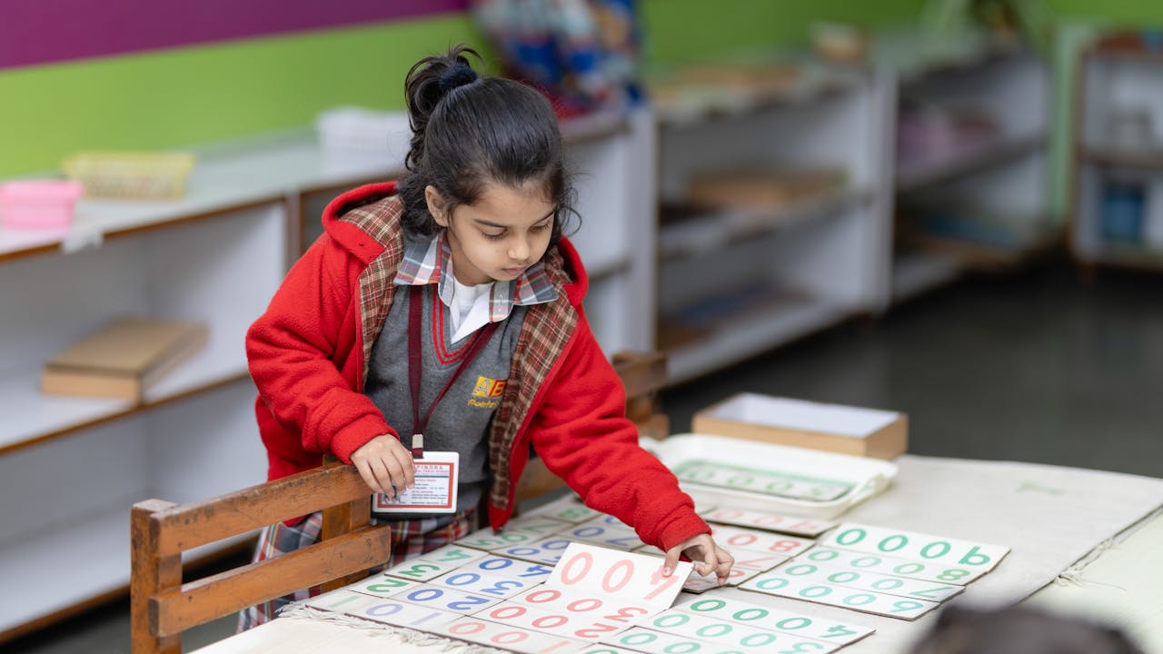A child concentrating on a Montessori number-card activity at a classroom table