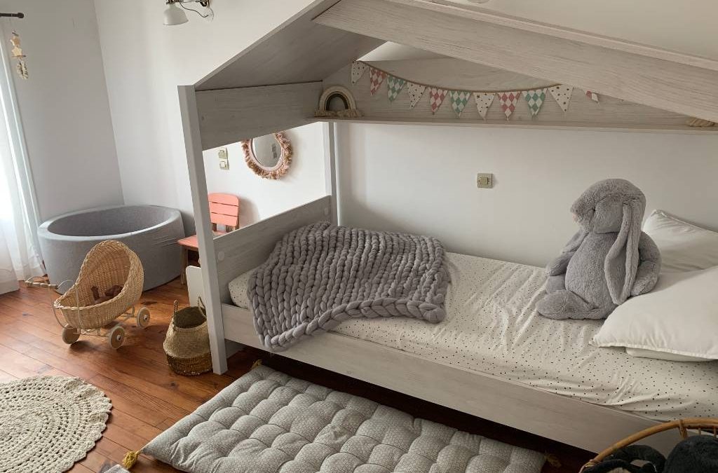 A calm, uncluttered Montessori bedroom with a floor bed, low shelves, and natural light