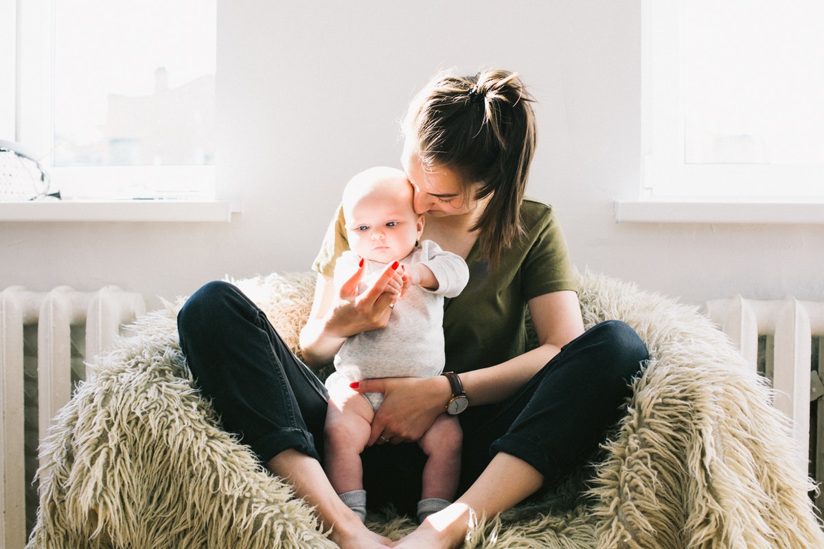 A parent gently holding and engaging with a young baby at home