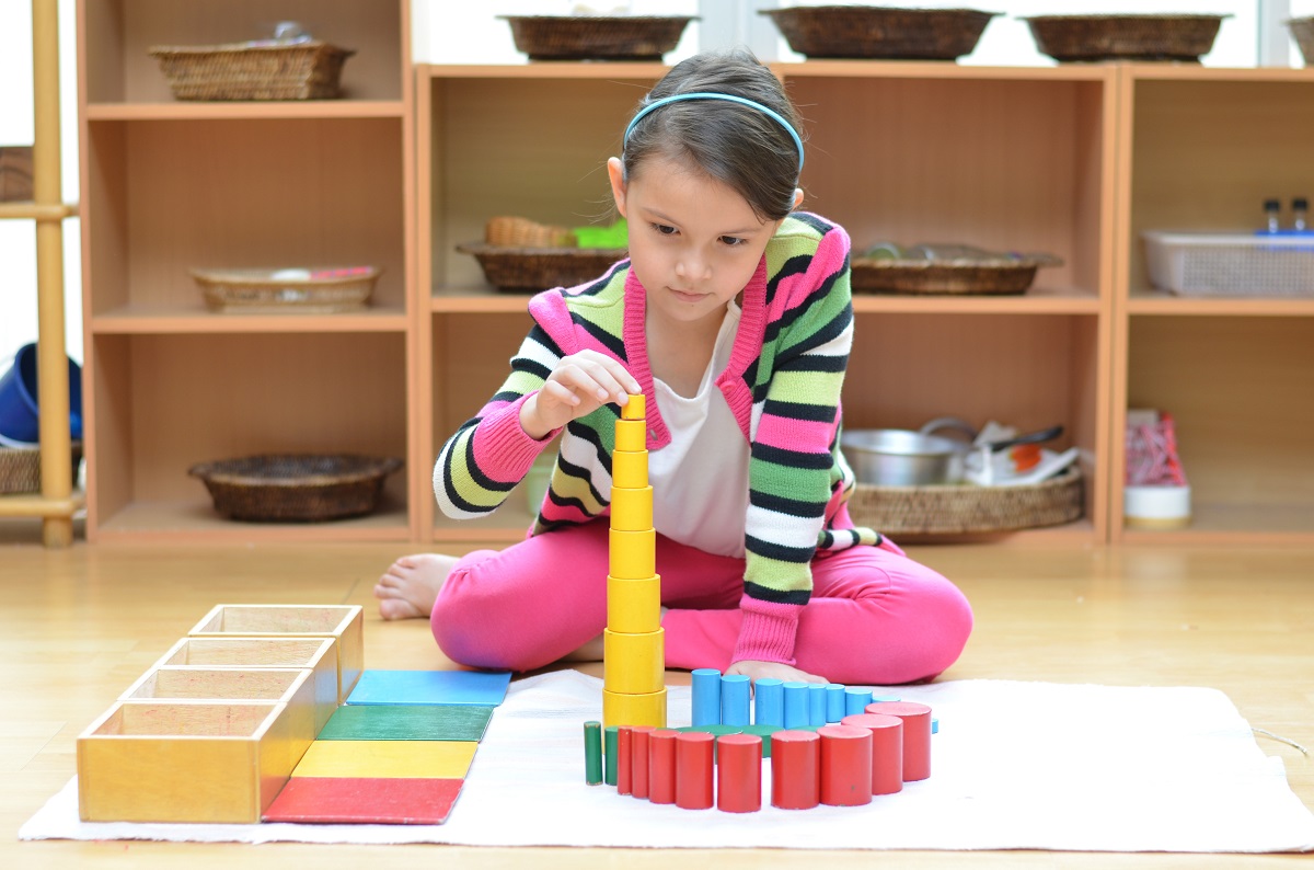 A child playing independently in a calm, uncluttered Montessori playroom with low shelves