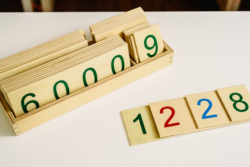 Close-up of a child's hand tracing a sandpaper number on a Montessori number card