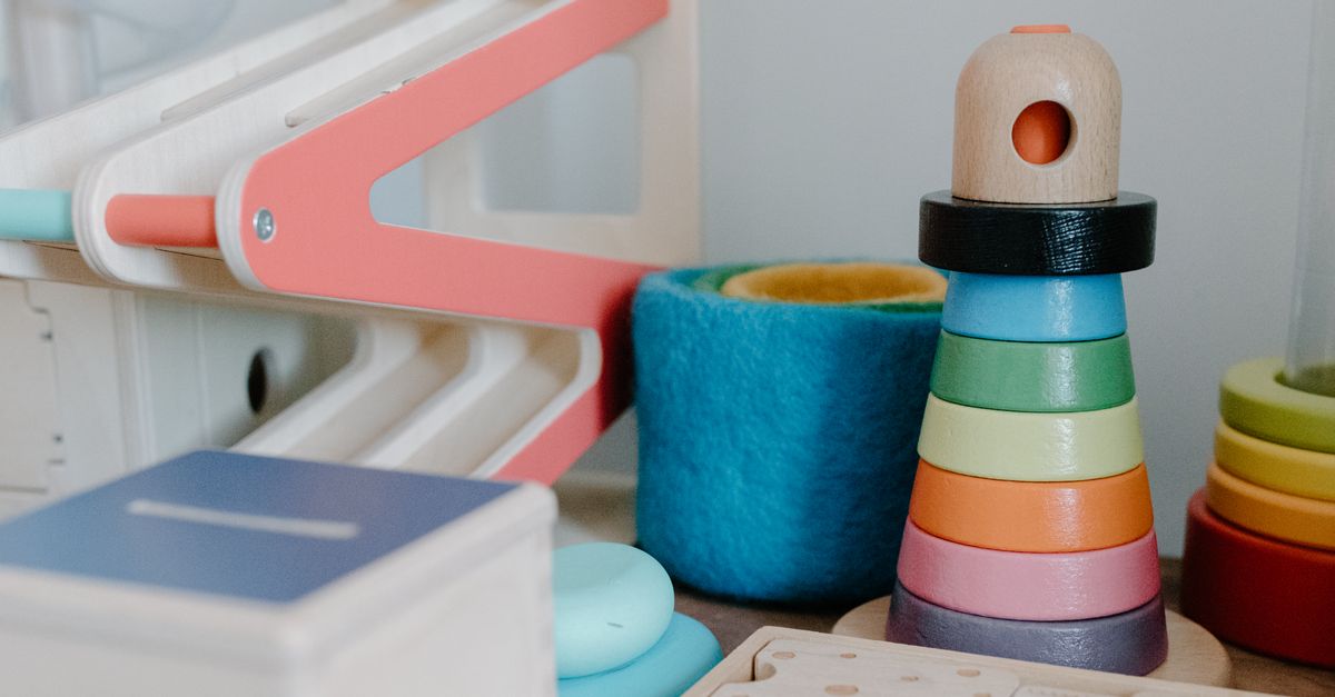 Wooden Montessori-aligned toys on a shelf, including a pastel stacking tower and a marble run