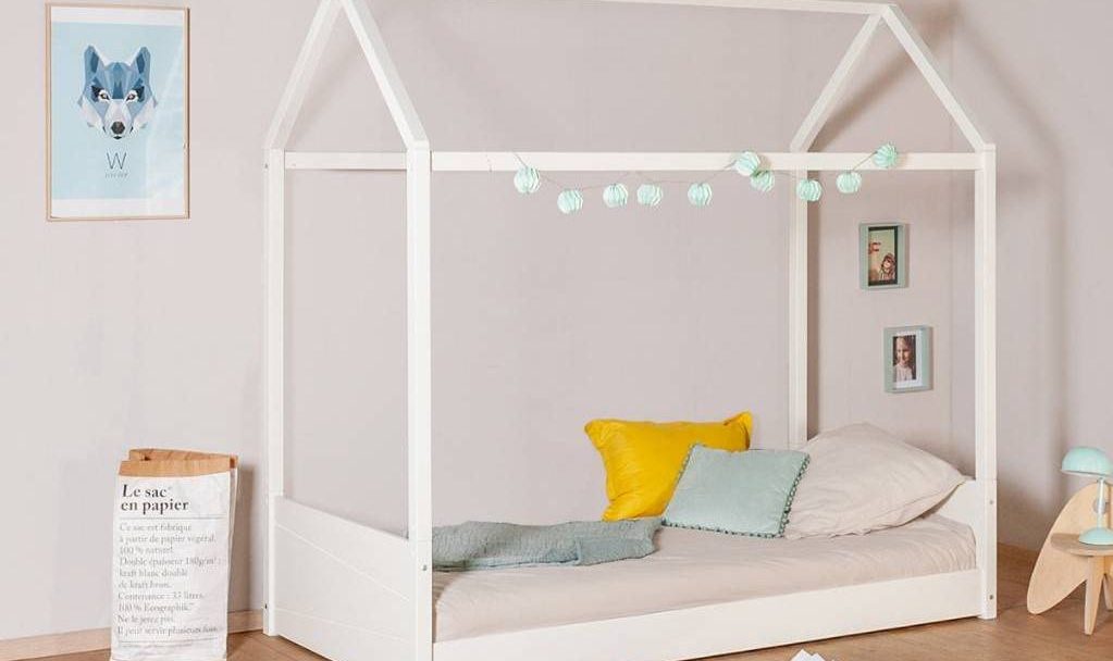 A calm, prepared child's bedroom with a low house-frame bed and simple, accessible furnishings