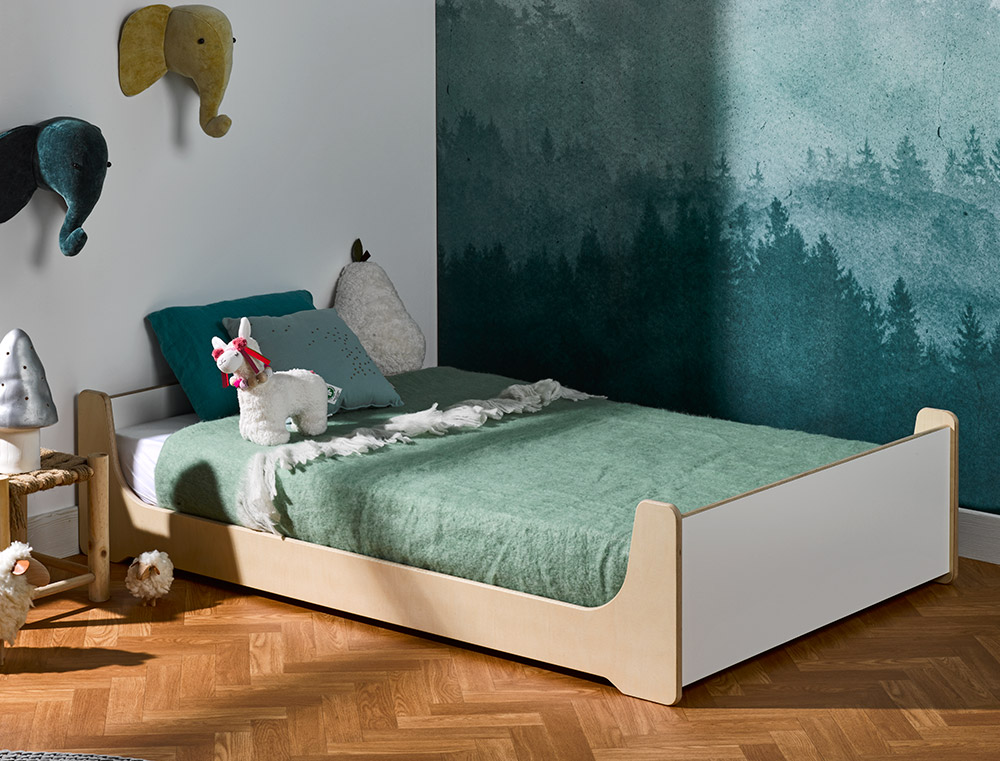 A low Montessori floor bed in a child's bedroom, easy for a young child to climb in and out of on their own